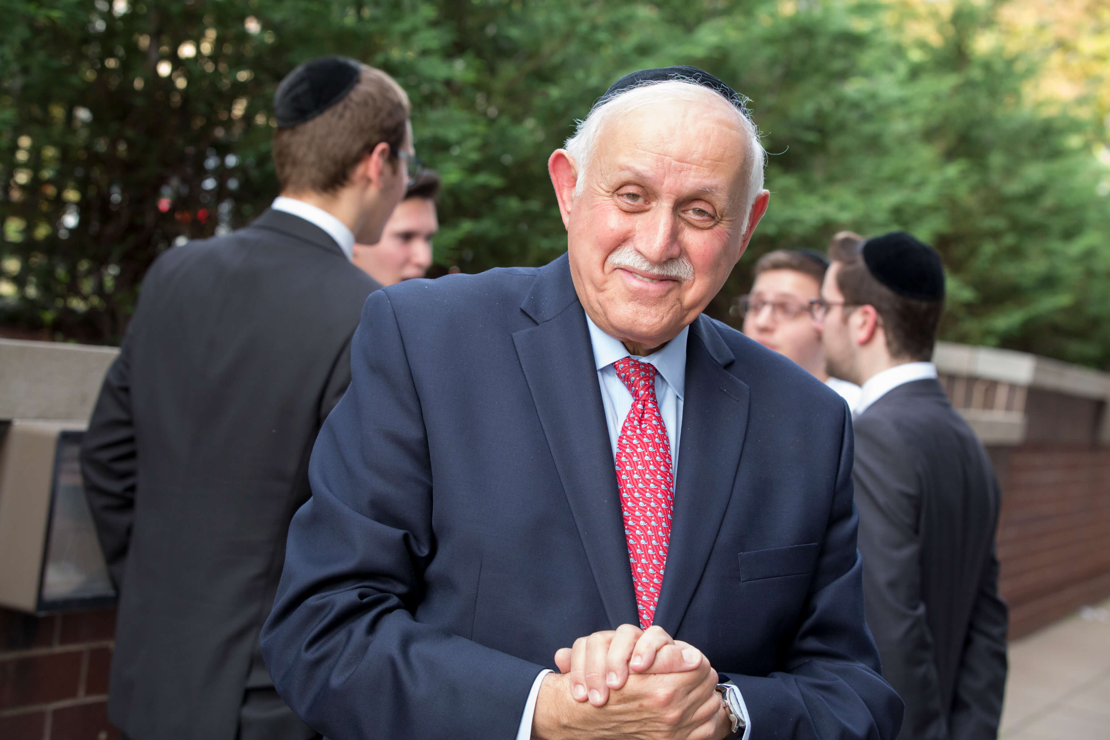 Dean Robert Goldschmidt outside, in suit and tie. Students are in the background.