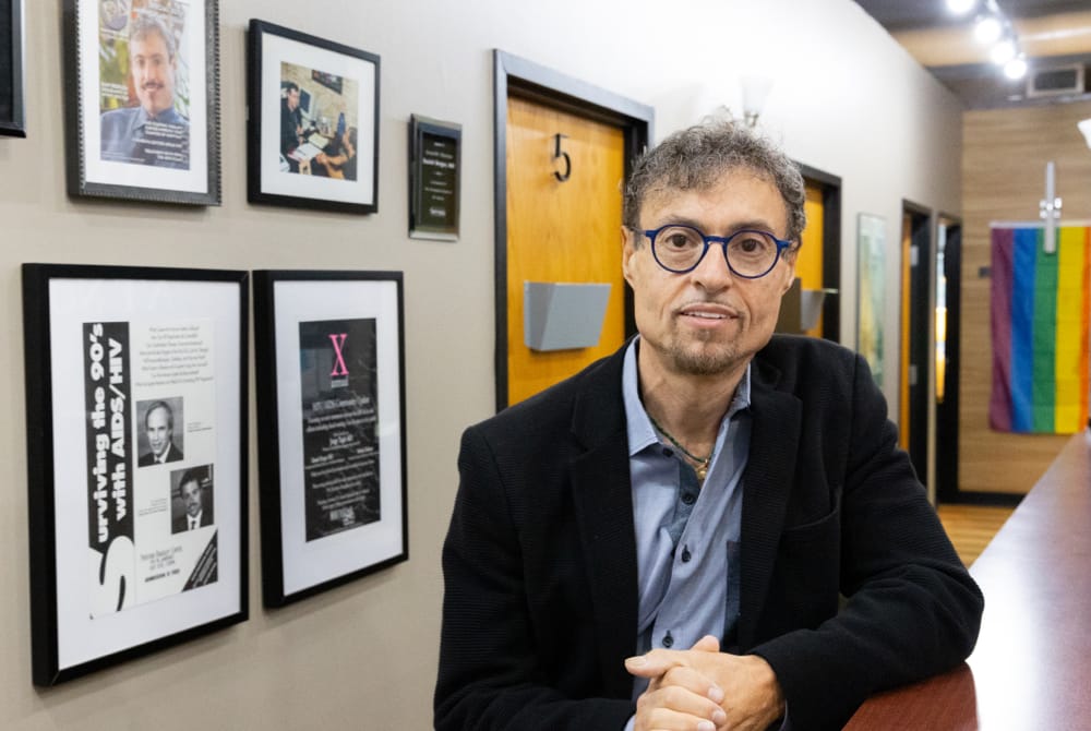 Dr. Daniel Berger posing in office in front of framed newspaper clippings.