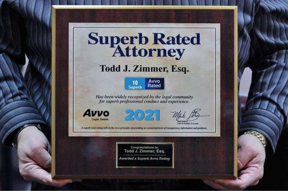 Man holding plaque that reads Superb Rated Attorney- Todd J. Zimmer, Esq. has been recognized by the legal community for superb professional conduct and experience. Awarded by Avvo in 2021.